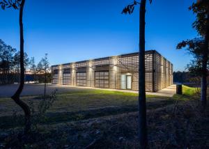 Photo of a boathouse lit at evening. The translucent exterior provides a lantern effect for the building.