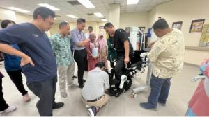 Therapist-led UGO exoskeleton trial at Hospital Sultanah Bahiyah: patient ambulating over ground while clinicians monitor posture, safety, and step symmetry.