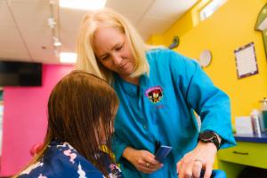 a stylist in a salon with a young girl in her chair.