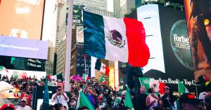 Large Mexican flag flying over a crowd gathered in Times Square for the “Latinos in Times Square” Hispanic Heritage Month event.