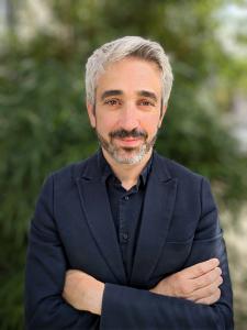 A photo of Anntao Diaz wearing a blue blazer and dark blue shirt.