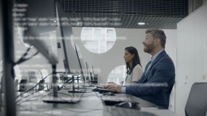 Two happy employees work effectively on computers.