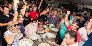Guests cheer as competitors in an oyster-eating contest dive into plates of oysters at Oyster Fest.