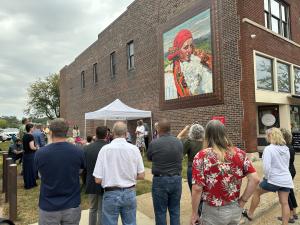 Art mural of a colorful woman with people spectating.