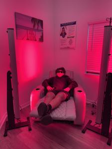 Person reclining in a chair between red light therapy panels, receiving a wellness treatment at South Beach Wellness Clinic in Lutz/Wesley Chapel