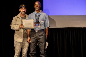 Film producer Scott Budnick presents the Best Short Documentary Pitch Award to incarcerated writer Kevin Sawyer, who is then newly appointed Editor in Chief of San Quentin News.