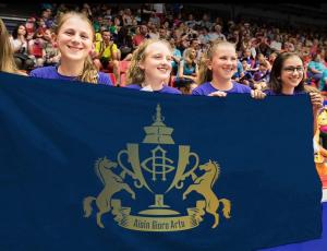 A group of young participants holding a flag with the Aisin Gioro Arts emblem, highlighting the prize’s focus on youth involvement and international cultural exchange