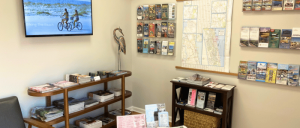 A cozy visitor center featuring brochures, maps, and a screen displaying a biking scene at the beach.