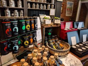 Shelves and tables inside The London Tea Room filled with tins of loose-leaf tea, spice jars with cork lids, baskets of tea canisters, and gift boxes. Signs and labels highlight different tea blends, with a cozy, vintage-style shop interior in the backgro