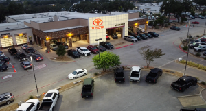 An exterior picture of Vic Vaughan Toyota of Boerne, owned by Vaughan Automotive before construction began. This picture includes vehicles from Toyota, as well as used vehicles and the signature Toyota sign.