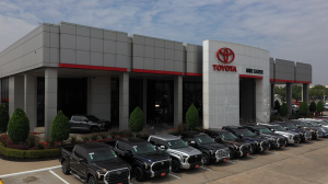 An exterior picture of Mike Calvert Toyota in Houston, Texas, Vaughan Automotive's 2nd Dealership acquisition on a cloudy day with a row of Tundras aligned in front of the store.