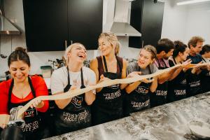 Group of friends laughing and making fresh pasta during a Selfup Boston cooking class.