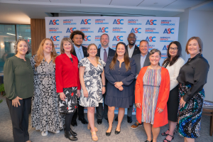 Group of ASC Board members standing next to each other smiling and in front of a backdrop with ASC logos.