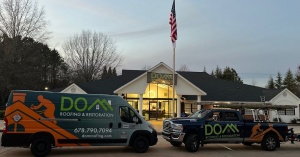 Dom Roofing & Restoration company vehicles parked outside office in Suwanee GA with American flag