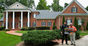 Homeowner standing with Dom Roofing & Restoration representative after new roof installation in Cumming Georgia