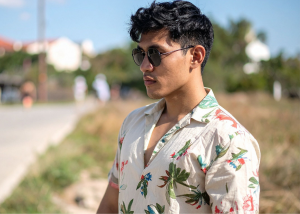 Young man wearing sunglasses and tropical floral print shirt in outdoor Hawaiian setting