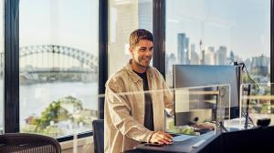 Man in office overlooking Sydney Harbout Bridge using computer