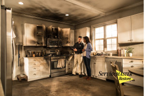 Restoration professional showing a homeowner extensive smoke and fire damage in a kitchen after a house fire.