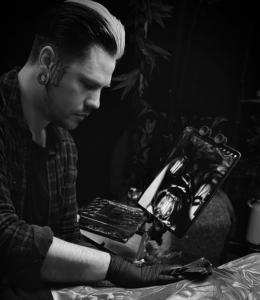 A photo of tattoo artist Owen Paulls working on a client