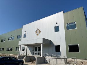 Exterior view of a building with a car parked in front under a blue sky.