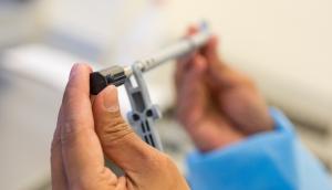 Close-up of an Aprios technician inspecting a small molded medical device component using precision tools inside the ISO Class 8 Clean Room in Vista, California.