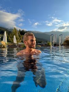 Mike Arens in an outdoor pool at Forsthofalm Leogang with mountain backdrop, representing Swiss luxury and mindful lifestyle aesthetics.