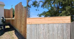Split yard showing a neighbor-friendly wood fence with a fold-down table and a tall privacy fence extension built by Tony’s Fencing in Covington, Louisiana.