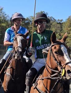 an arena polo player from Italy and an arena polo player from Pakistan execute a defensive ride-off on horses