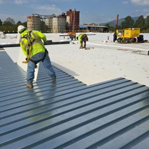 Installing new insulation and metal decking on an industrial roof