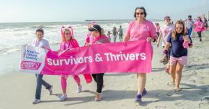 People walking on the beach holding a banner.