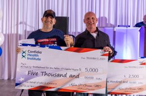 Dr. Kevin Greene of Confidia Health Institute presents a $5,000 donation during the Confidia Cares: Honor Our Heroes Celebration.