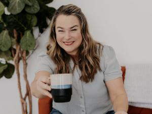 Jennifer Wren Tolo, founder of Butterfly Family Wellness and Transformational Life Coach, smiles while holding a mug as she launches her new online course “Permission to Pause,” helping women reset their nervous systems and find calm. Photo Credit: Nicole Perfeteo