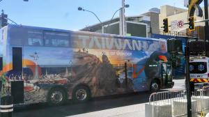 Taiwan Tourism bus advertisement featuring Lanyu canoes, Nanya Rock formations, and the majestic Qingshui Cliffs.