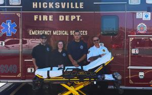 Photograph of Hicksville Fire District EMS providers standing with an ambulance gurney equipped with Hinckley Medical’s OneWeight® patient scale.
