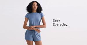 A woman wearing a matching blue loungewear set consisting of a short-sleeved top and shorts, standing against a plain background with the text “Easy Everyday.” displayed beside her.