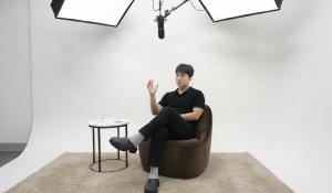 Austin KOO, CEO of Airet, seated on a modern sofa in a bright white cyclorama studio, actively engaged in an interview discussion.