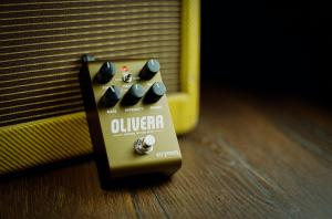 Image shows the Olivera oil can echo propped up against a vintage tweed amplifier