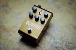 Image shows the Olivera oil can echo pedal sitting on a vintage metal table top