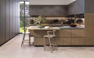 Modern kitchen with light oak cabinets, porcelain-look counters and backsplash, integrated lighting, and peninsula seating.