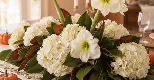 Low sophisticated Thanksgiving centerpiece with glossy magnolia leaves, white hydrangeas, and cream amaryllis in wide decorative bowl for Southern table
