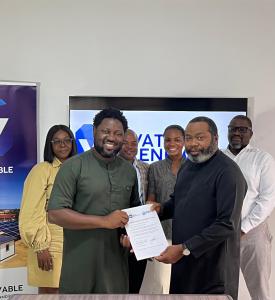 Representatives from WATT Renewable Corporation and MPS Technologies pose in an office as the Leader of the companies are at the front jointly holding and display a signed agreement; a screen behind shows the WATT Renewable logo and a banner by the side.