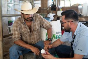 Image shows Carlos Tabora providing guidance to a livestock producer in Olancho, Honduras.