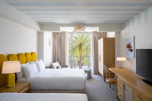 Interior of a modern guest room at Renaissance Orlando Resort & Spa at Disney Springs®, showcasing two queen beds, stylish furnishings, and a view of palm trees by the pool.