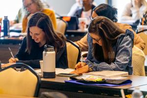 Participants in a PECS training are smiling and taking notes