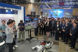 A group of government officials and other invited guests observing a demo of a quadrupedal firefighting robot.