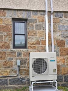 Fujitsu ducted heat pump condenser installed outside a residential home in Milton, Massachusetts in 2024 by Green Energy Mechanical.