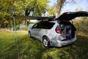2026 Mini-T Campervan by DLM-Distribution with awning extended at a scenic lakeside campsite, showcasing its compact, garageable Class B RV design.