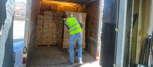 Leonardo Vargas, Head of Sales at Grunber, stands inside a truck organizing a large stack of cardboard boxes.