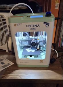 The printer is placed on a table at home, printing a model.
