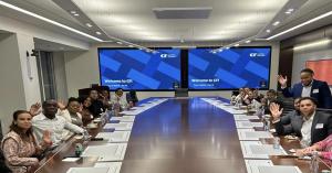 A group of Onyx Initiative students seated around a large boardroom table, smiling and waving during a corporate workshop.